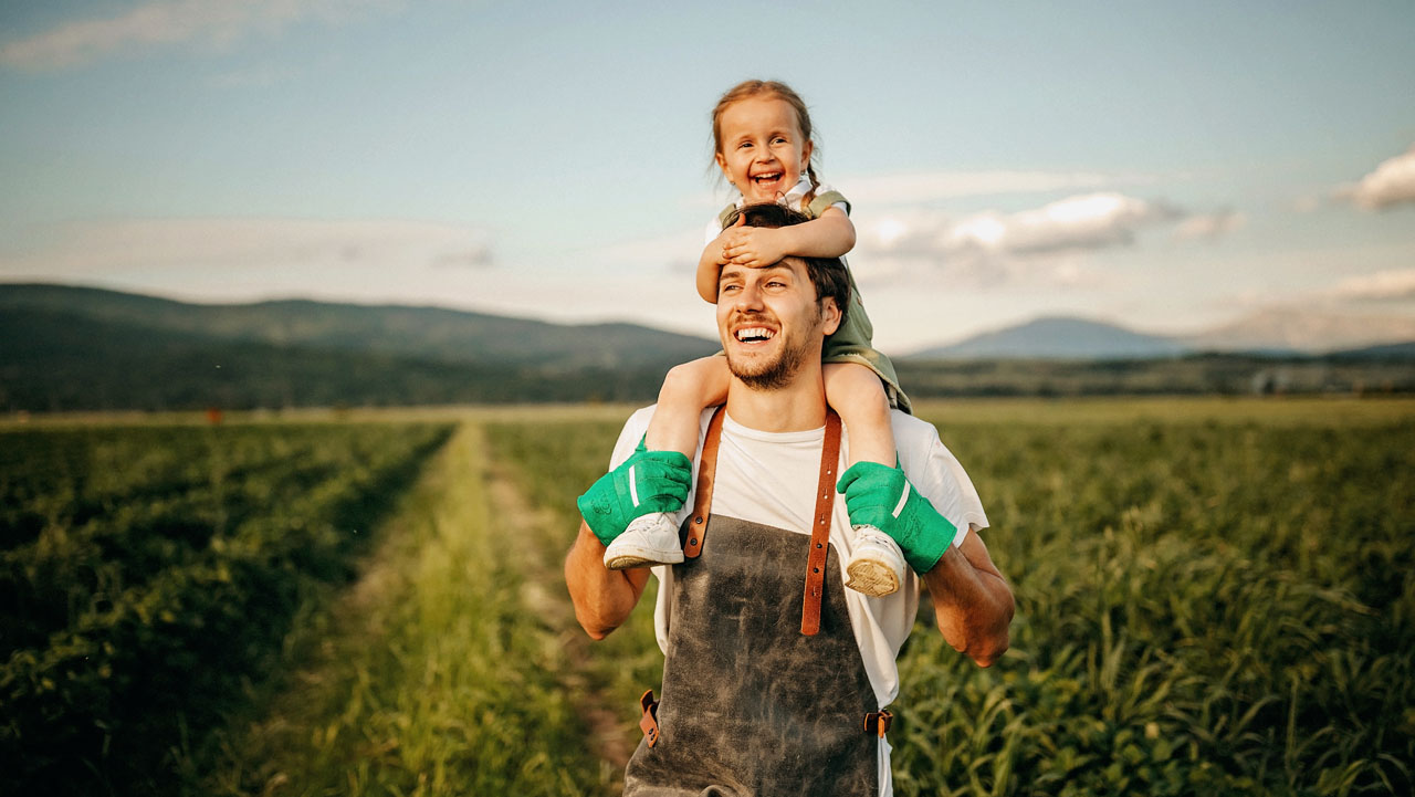 Father carrying his daughter on the farm land